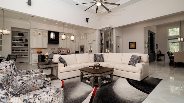 living room with built in shelves, ceiling fan, ornamental molding, and a towering ceiling