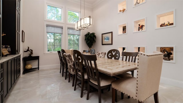 9260 Swaying Branch Rd, Sarasota, FL 34241 - dining room featuring a towering ceiling, baseboards, crown molding, and light marble finish floors