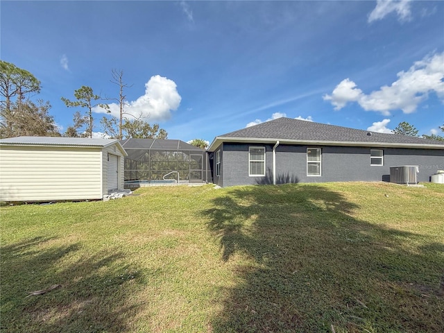 back of house with central AC unit, glass enclosure, a swimming pool, and a yard