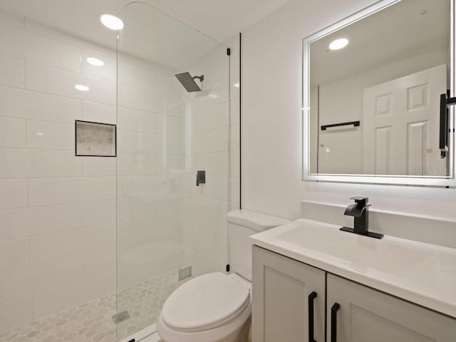 bathroom featuring toilet, vanity, and a tile shower