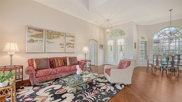 living room with french doors, an inviting chandelier, hardwood / wood-style floors, crown molding, and a high ceiling