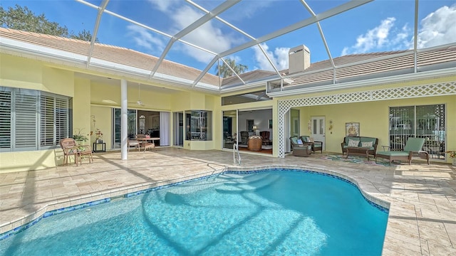 view of swimming pool with glass enclosure, ceiling fan, an outdoor hangout area, and a patio area