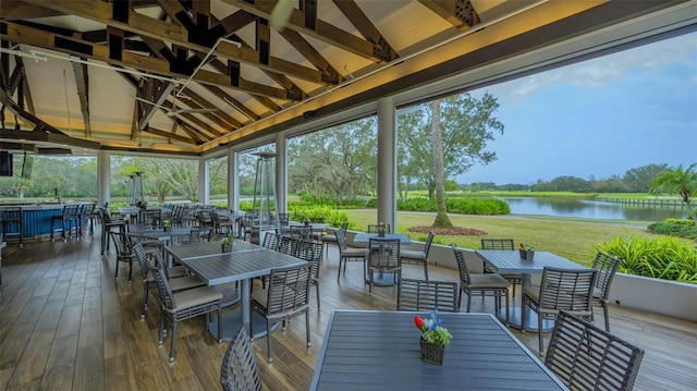sunroom / solarium featuring outdoor dining space, a water view, and view of wooded area