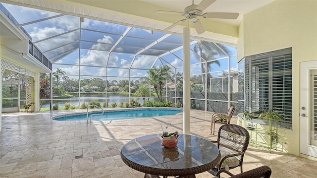 outdoor pool featuring a patio, a ceiling fan, glass enclosure, and a water view