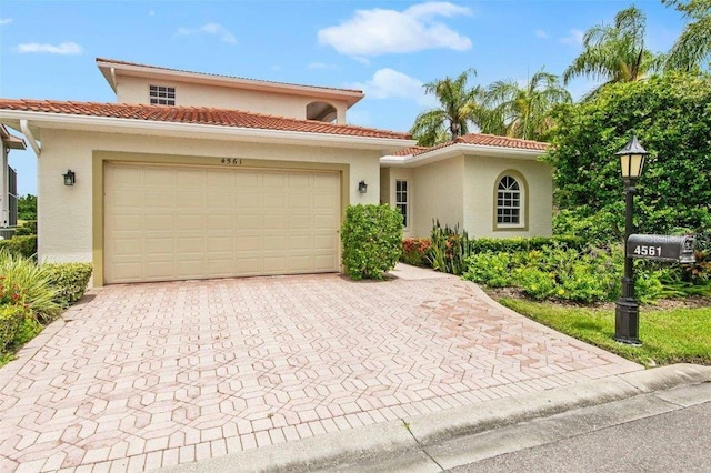 4561 Murcia Blvd Unit 13, Sarasota, FL 34238 - mediterranean / spanish-style house featuring stucco siding, decorative driveway, an attached garage, and a tiled roof