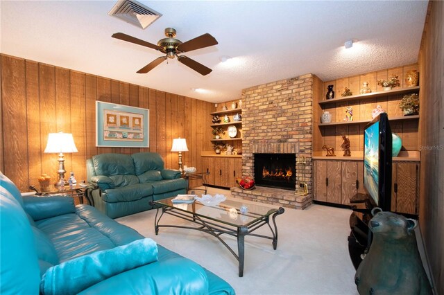 living room with a fireplace, a textured ceiling, wood walls, light colored carpet, and ceiling fan