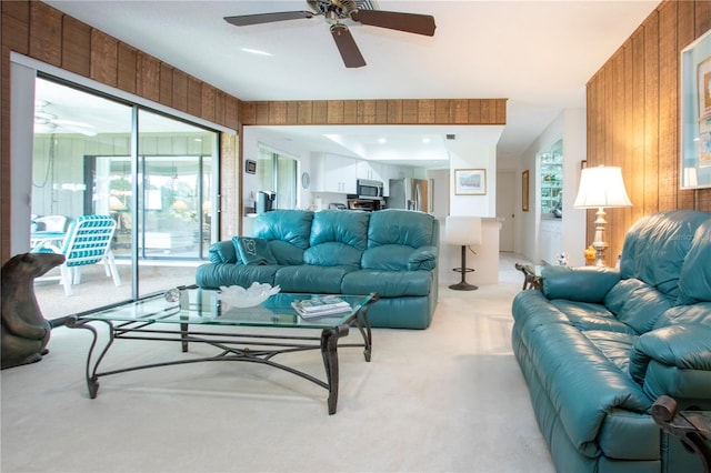 carpeted living room with wood walls and ceiling fan