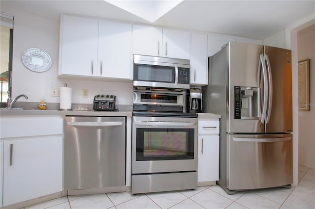 kitchen featuring white cabinetry, sink, light tile patterned floors, and stainless steel appliances