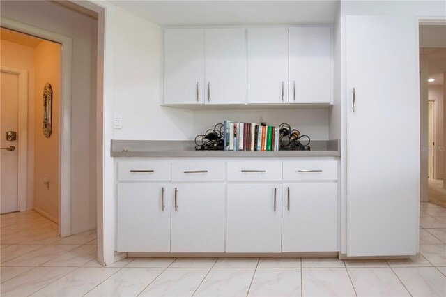 bar featuring white cabinetry and light tile patterned flooring