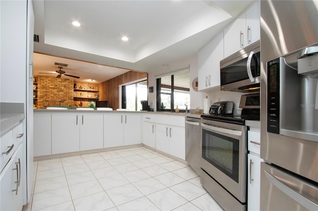 kitchen featuring stainless steel appliances, white cabinets, and a raised ceiling