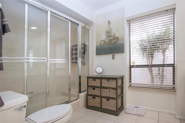 bathroom with tile patterned flooring, combined bath / shower with glass door, and toilet