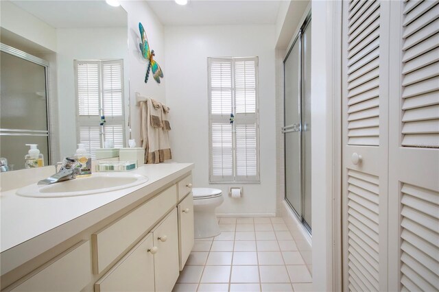 bathroom with vanity, a shower with door, tile patterned flooring, and toilet