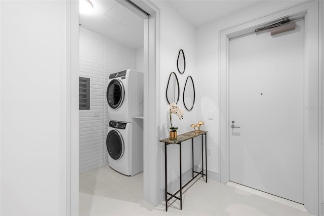 clothes washing area featuring stacked washing maching and dryer and light tile patterned floors