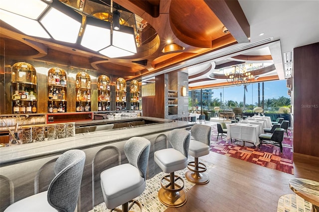 bar featuring hardwood / wood-style floors and an inviting chandelier