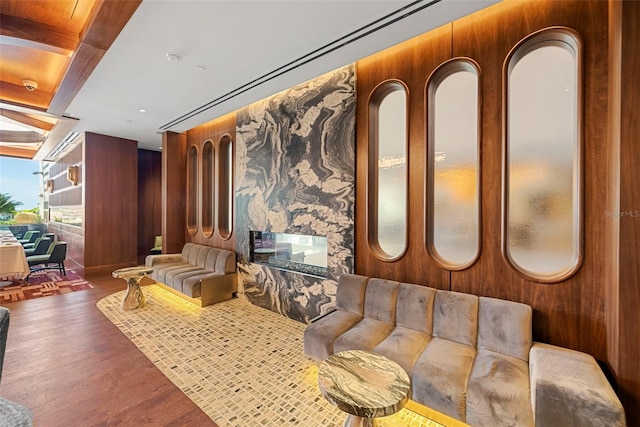 sitting room with a premium fireplace, wood walls, dark hardwood / wood-style floors, and beam ceiling