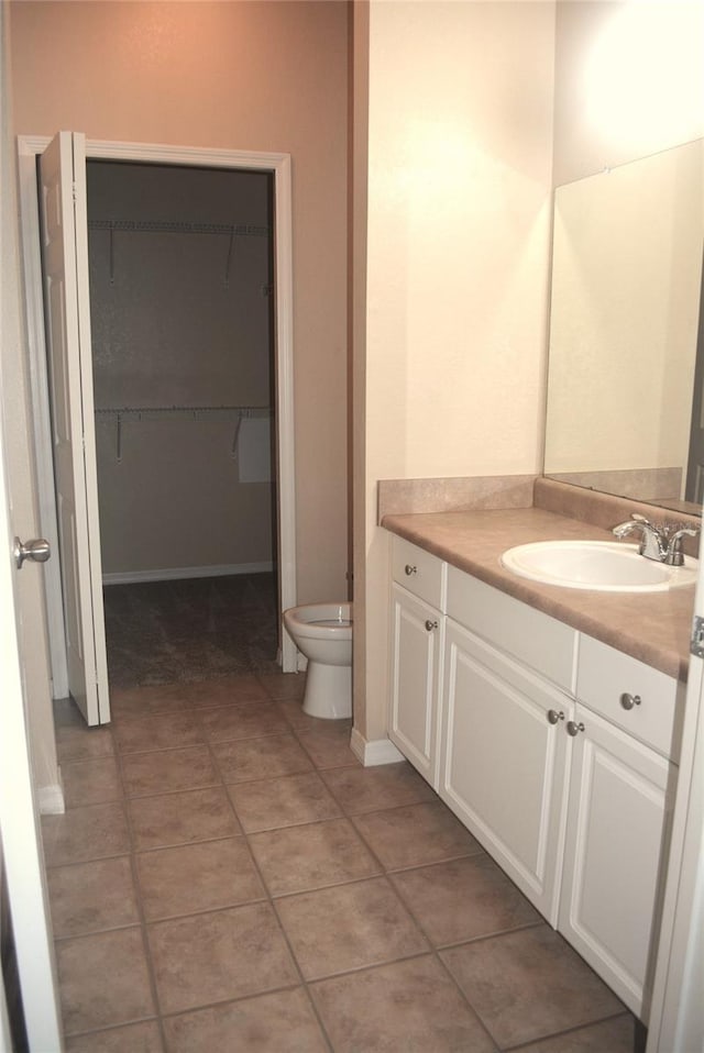 bathroom with toilet, vanity, and tile patterned floors