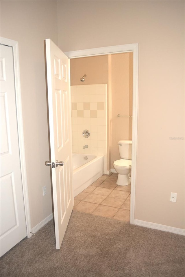 bathroom featuring tile patterned flooring, tiled shower / bath, and toilet