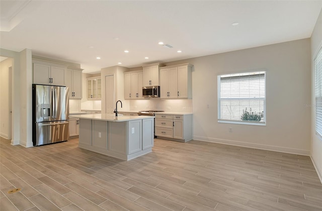 kitchen featuring appliances with stainless steel finishes, light hardwood / wood-style floors, a kitchen island with sink, and sink