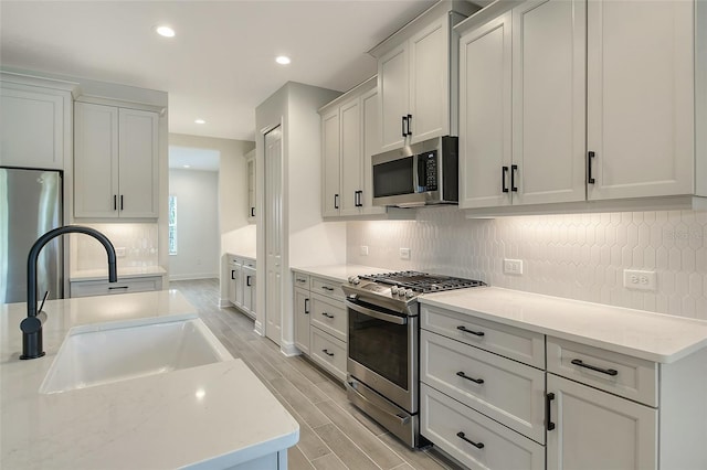 kitchen featuring light stone counters, sink, white cabinets, and stainless steel appliances