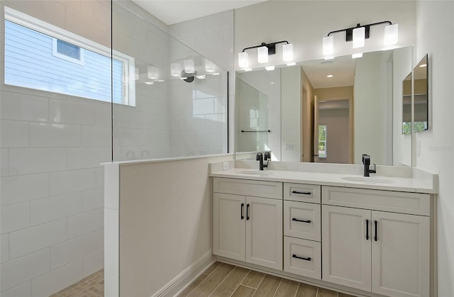 bathroom featuring a tile shower, vanity, and a wealth of natural light