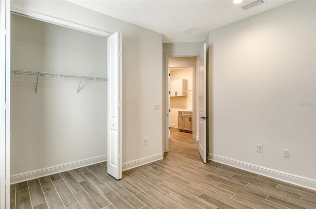 unfurnished bedroom featuring light hardwood / wood-style flooring and a closet