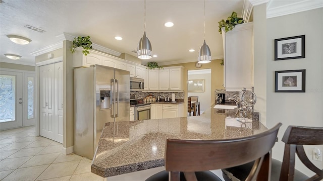 134 Da Vinci Dr, Nokomis, FL 34275 - kitchen featuring appliances with stainless steel finishes, a peninsula, ornamental molding, decorative backsplash, and a kitchen breakfast bar