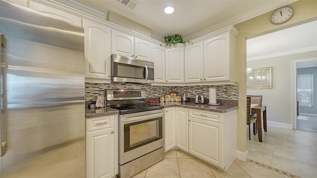 kitchen with white cabinets, decorative backsplash, appliances with stainless steel finishes, and dark stone countertops