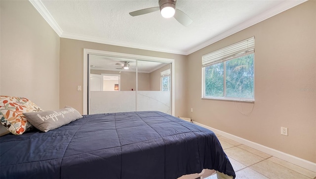 bedroom with ornamental molding, ceiling fan, a textured ceiling, light tile patterned floors, and a closet