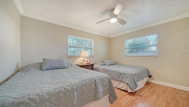 bedroom featuring ceiling fan, a textured ceiling, light hardwood / wood-style flooring, and ornamental molding