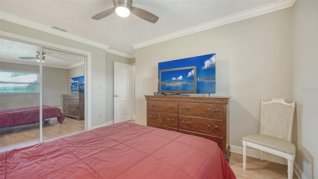 bedroom featuring hardwood / wood-style flooring, ornamental molding, ceiling fan, and a closet