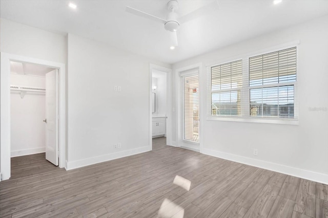 unfurnished bedroom featuring ceiling fan, a closet, a spacious closet, and hardwood / wood-style flooring