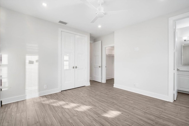 unfurnished bedroom featuring connected bathroom, ceiling fan, and light wood-type flooring