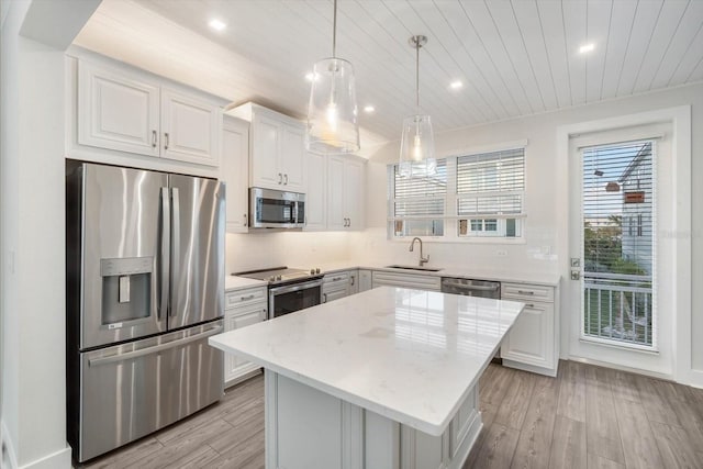 kitchen featuring white cabinetry, sink, stainless steel appliances, pendant lighting, and a kitchen island