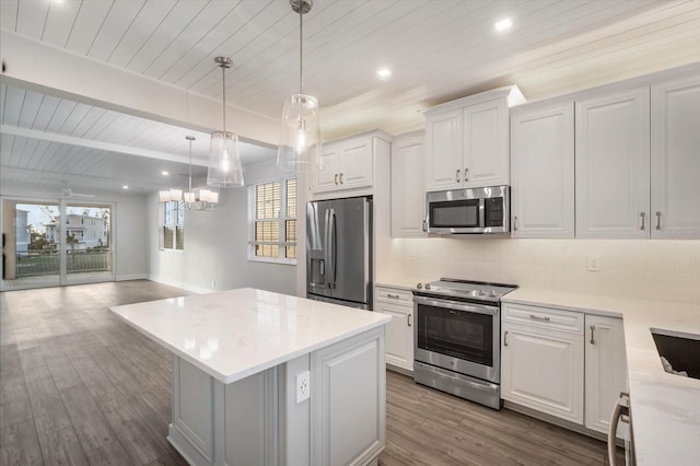 kitchen featuring beam ceiling, white cabinetry, stainless steel appliances, decorative light fixtures, and light wood-type flooring