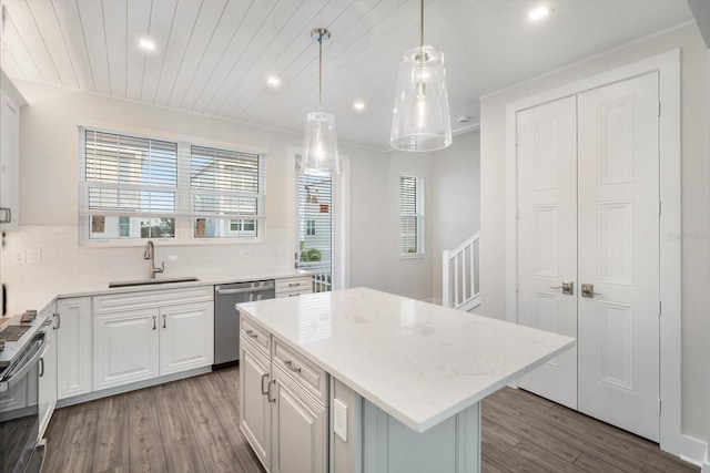 kitchen featuring a kitchen island, sink, pendant lighting, dishwasher, and white cabinetry