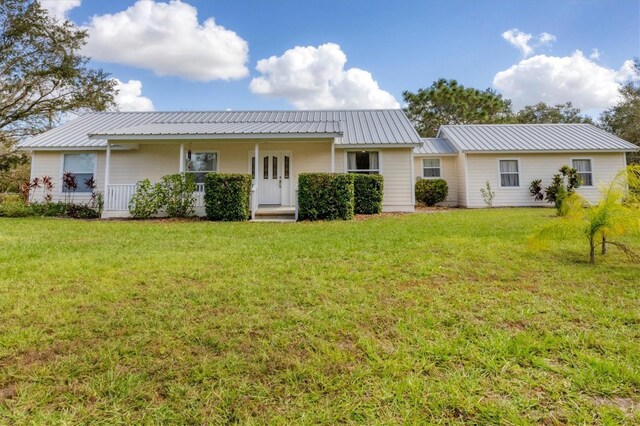 back of property with a yard, metal roof, and a porch