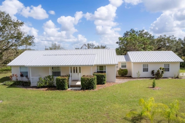 back of property featuring a porch, metal roof, and a lawn