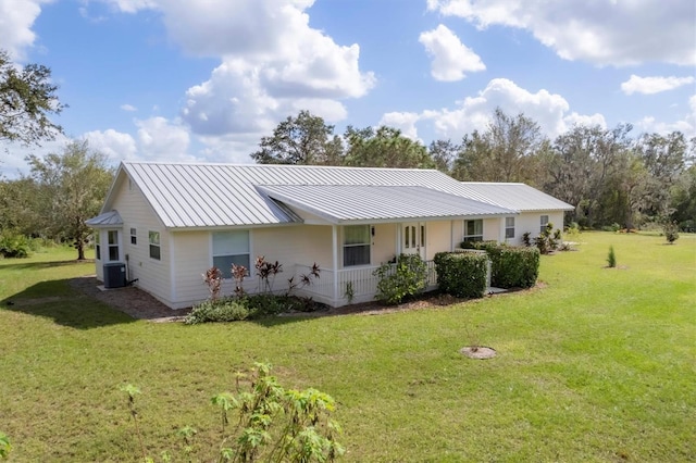 back of property with a yard, central air condition unit, a porch, and metal roof