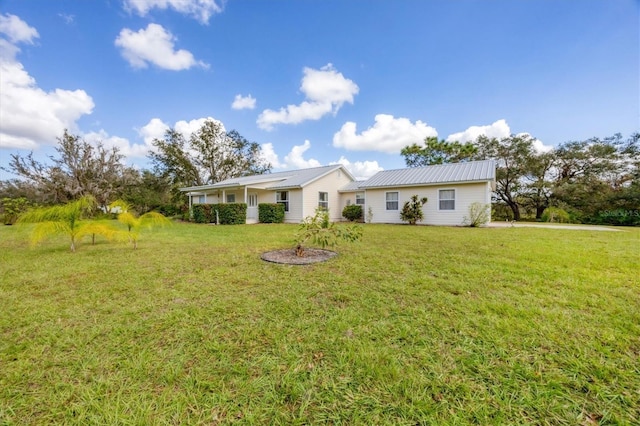 back of property featuring a lawn and metal roof