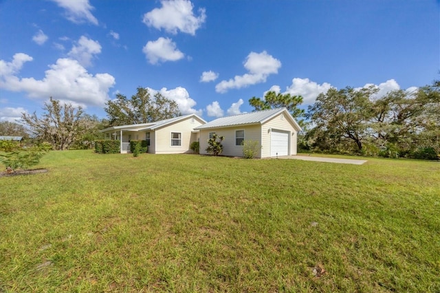 exterior space with metal roof, a garage, a front lawn, and driveway
