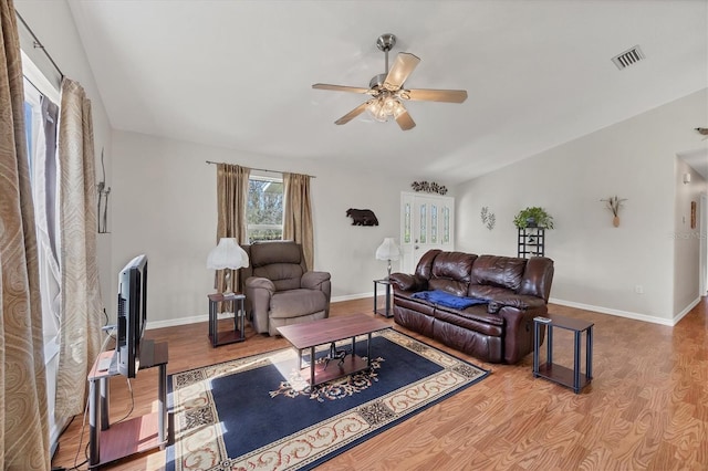 living room with visible vents, wood finished floors, baseboards, and ceiling fan