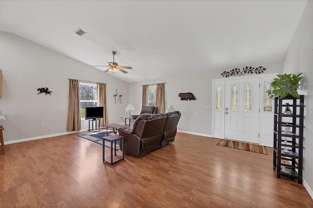 living area featuring wood finished floors, visible vents, baseboards, ceiling fan, and vaulted ceiling