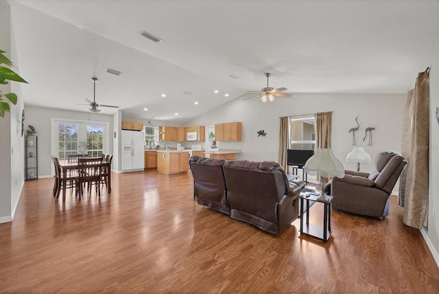 living room with light wood-type flooring, visible vents, lofted ceiling, and ceiling fan