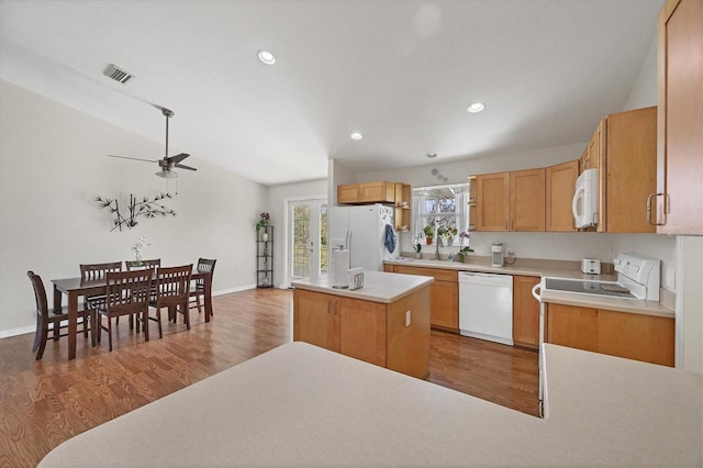 kitchen with wood finished floors, a ceiling fan, a sink, and white appliances