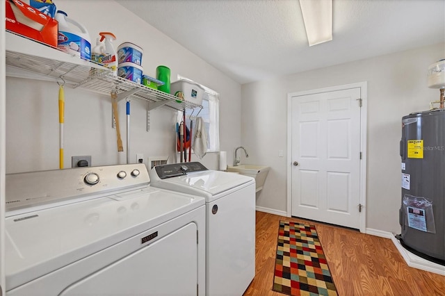 laundry room featuring sink, a textured ceiling, light hardwood / wood-style flooring, washer and dryer, and water heater