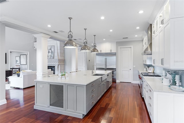 kitchen with wall chimney exhaust hood, pendant lighting, and white cabinets