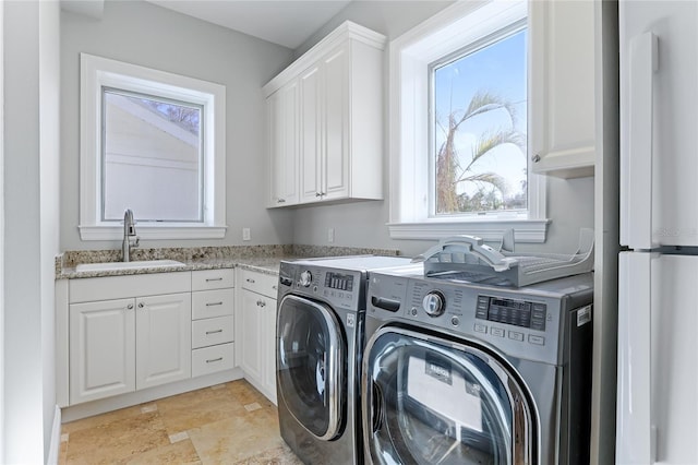 clothes washing area featuring a healthy amount of sunlight, independent washer and dryer, sink, and cabinets