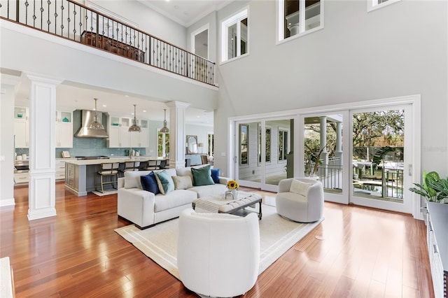 living room featuring decorative columns, light hardwood / wood-style floors, and a towering ceiling