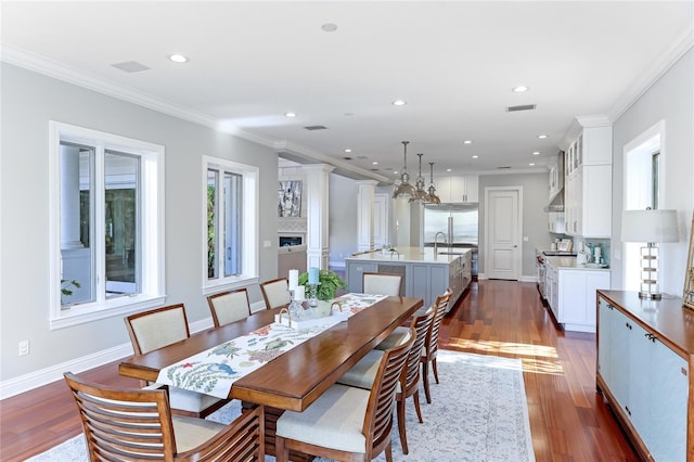 dining area featuring dark wood-type flooring, ornamental molding, and sink