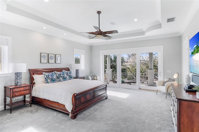 carpeted bedroom with access to outside, ceiling fan, a tray ceiling, and multiple windows